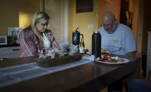 Cari-Ann Burgess, interim Registrar of Voters for Washoe County, Nev., left, prays with her husband Shane Burgess before eating dinner at their home Friday, Sept. 20, 2024, in Reno, Nev. (AP Photo/John Locher)