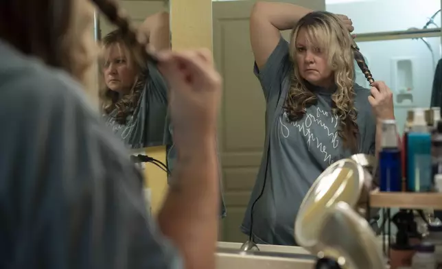 Cari-Ann Burgess, interim Registrar of Voters for Washoe County, Nev., curls her hair before church on Sunday, Sept. 22, 2024, in Reno, Nevada. (AP Photo/Serkan Gurbuz)