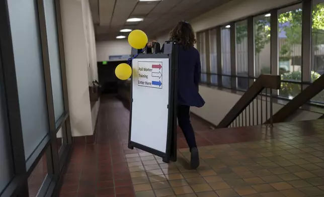 Wendy Steiner, office assistant at the Washoe County Registrar of Voters office, carries a sign for poll worker training Saturday, Sept. 21, 2024, in Reno, Nev. (AP Photo/John Locher)