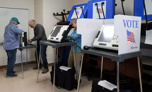 Poll workers set up ballot-marking machines at an early in-person voting site at Asheville-Buncombe Technical Community College, Wednesday, Oct. 16, 2024, in Marshall, N.C. (AP Photo/Stephanie Scarbrough)