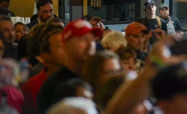 Employees of a restaurant, top right, listen with a crowd during a campaign event for Sen. Ted Cruz, R-Texas, Saturday, Oct. 5, 2024, in Keller, Texas. (AP Photo/Julio Cortez)