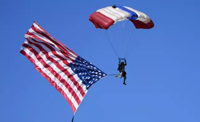 A parachuter with an American flag descends over a campaign event for Republican presidential nominee former President Donald Trump at the Butler Farm Show, Saturday, Oct. 5, 2024, in Butler, Pa. (AP Photo/Alex Brandon)