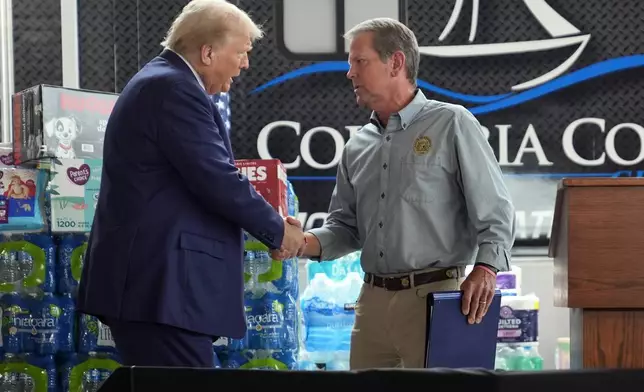 Republican presidential nominee former President Donald Trump shakes hands with Georgia Gov. Brian Kemp at a temporary relief shelter as he visits areas impacted by Hurricane Helene, Friday, Oct. 4, 2024, in Evans, Ga. (AP Photo/Evan Vucci)