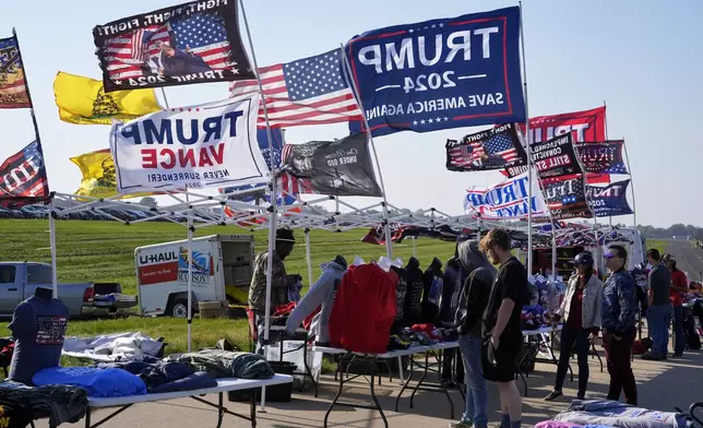 Supporters look at merchandise before Republican presidential nominee former President Donald Trump speaks at a campaign stop at the Dodge County Airport Sunday, Oct. 6, 2024, in Juneau, Wis. (AP Photo/Morry Gash)