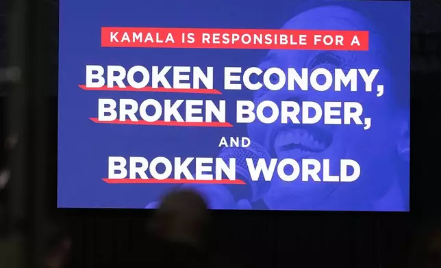 A message about Democratic presidential nominee Vice President Kamala Harris appears on a video screen before Republican presidential nominee former President Donald Trump speaks at a campaign rally at the Gaylord Rockies Resort and Convention Center Friday, Oct. 11, 2024, in Aurora, Colo. (AP Photo/David Zalubowski)