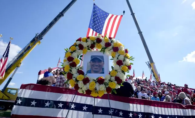 A memorial for firefighter Corey Comperatore, who died as he shielded family members from gunfire, is seen in the bleachers as attendees arrive before Republican presidential nominee former President Donald Trump speaks at the Butler Farm Show, the site where a gunman tried to assassinate Trump in July, Saturday, Oct. 5, 2024, in Butler, Pa. (AP Photo/Alex Brandon)