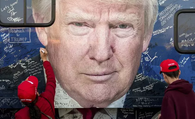 Supporters of Republican presidential nominee former President Donald Trump sign a bus before a campaign rally at the Butler Farm Show, Saturday, Oct. 5, 2024, in Butler, Pa. (AP Photo/Julia Demaree Nikhinson)