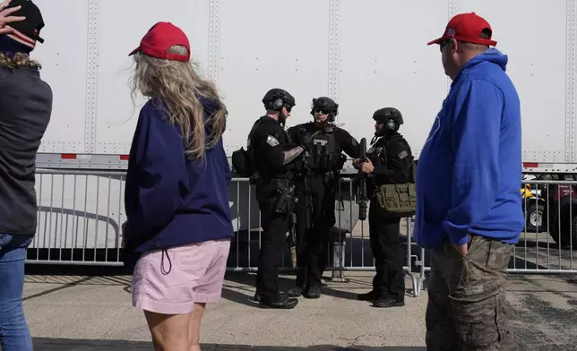 Members of law enforcement talk as people wait for Republican presidential nominee former President Donald Trump to speak during a campaign rally at Dodge County Airport, Sunday, Oct. 6, 2024, in Juneau, Wis. (AP Photo/Julia Demaree Nikhinson)