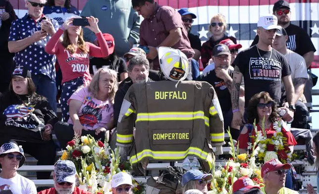 A memorial for firefighter Corey Comperatore, who died as he shielded family members from gunfire, is seen in the bleachers as attendees arrive before Republican presidential nominee former President Donald Trump speaks at the Butler Farm Show, the site where a gunman tried to assassinate Trump in July, Saturday, Oct. 5, 2024, in Butler, Pa. (AP Photo/Alex Brandon)