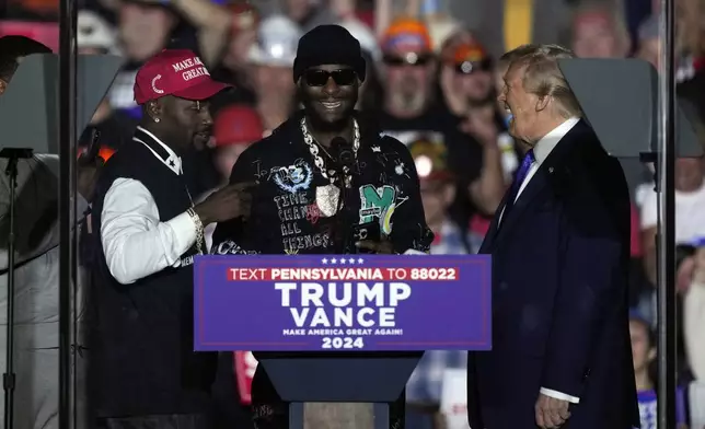 Republican presidential nominee former President Donald Trump listens to former Pittsburgh Steelers Antonio Brown, left, and, Le'Veon Bell, at a campaign rally, Saturday, Oct. 19, 2024, at Arnold Palmer Regional Airport in Latrobe, Pa. (AP Photo/Matt Rourke)