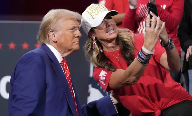 Republican presidential nominee former President Donald Trump poses for a photo with a supporter at a campaign event at the Cobb Energy Performing Arts Centre, Tuesday, Oct. 15, 2024, in Atlanta. (AP Photo/Alex Brandon)