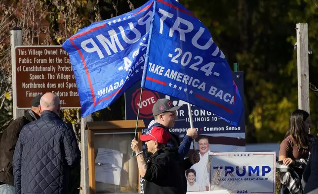 Supporters of Republican presidential nominee former President Donald Trump hold up flags during a Trump rally in Northbrook, Ill., Sunday, Oct. 27, 2024. (AP Photo/Nam Y. Huh)