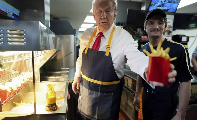 Republican presidential nominee former President Donald Trump, left, hands off an order of fries after working alongside an employee during a visit to McDonald's in Feasterville-Trevose, Pa., Sunday, Oct. 20, 2024. (Doug Mills/The New York Times via AP, Pool)