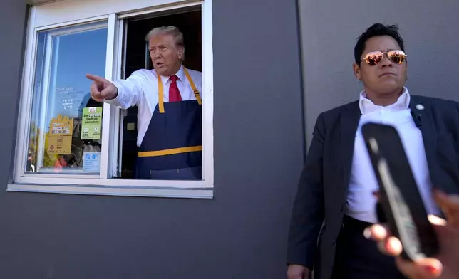 Republican presidential nominee former President Donald Trump points from a drive-thru window as a member of the Secret Service looks on during a campaign stop at a McDonald's, Sunday, Oct. 20, 2024, in Feasterville-Trevose, Pa. (AP Photo/Evan Vucci)