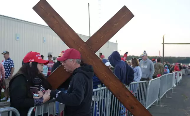 Dan Beasley of Northville, Mich., prays with Sue Hensal of Akron, Ohio, before Republican presidential nominee former President Donald Trump speaks at a campaign rally at the Butler Farm Show, the site where a gunman tried to assassinate him in July, Saturday, Oct. 5, 2024, in Butler, Pa. (AP Photo/Alex Brandon)