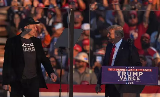 Elon Musk jumps on the stage behind Republican presidential nominee former President Donald Trump during a campaign rally at the Butler Farm Show, Saturday, Oct. 5, 2024, in Butler, Pa. (AP Photo/Julia Demaree Nikhinson)