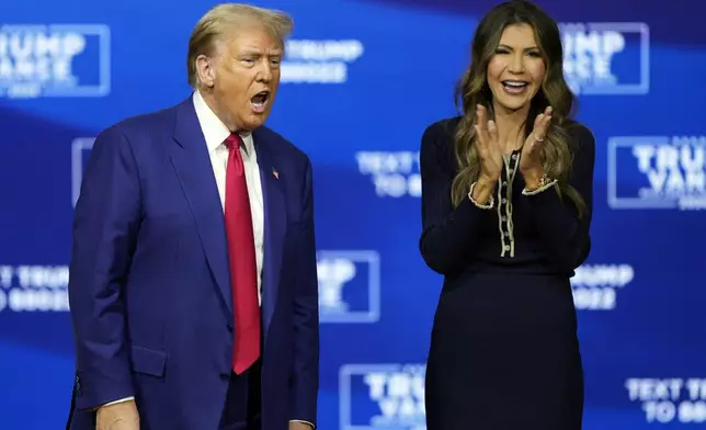 Republican presidential nominee former President Donald Trump arrives at a campaign town hall at the Greater Philadelphia Expo Center &amp; Fairgrounds, Monday, Oct. 14, 2024, in Oaks, Pa., as moderator South Dakota Gov. Kristi Noem watches. (AP Photo/Matt Rourke)