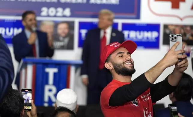 A supporter takes a photo as Republican presidential nominee former President Donald Trump visits a campaign office, Friday, Oct. 18, 2024, in Hamtramck, Mich. (AP Photo/Evan Vucci)