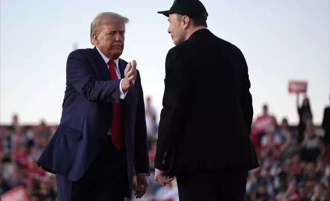 Republican presidential nominee former President Donald Trump shakes hands with Elon Musk at a campaign rally at the Butler Farm Show, Saturday, Oct. 5, 2024, in Butler, Pa. (AP Photo/Evan Vucci)