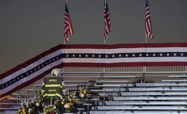 A memorial for firefighter Corey Comperatore, who died as he shielded family members from gunfire, is seen in the bleachers before Republican presidential nominee former President Donald Trump speaks at the Butler Farm Show, the site where a gunman tried to assassinate him in July, Saturday, Oct. 5, 2024, in Butler, Pa. (AP Photo/Alex Brandon)