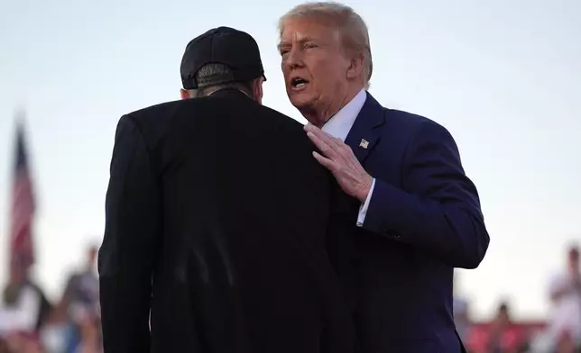 Republican presidential nominee former President Donald Trump shakes hands with Elon Musk at a campaign rally at the Butler Farm Show, Saturday, Oct. 5, 2024, in Butler, Pa. (AP Photo/Evan Vucci)