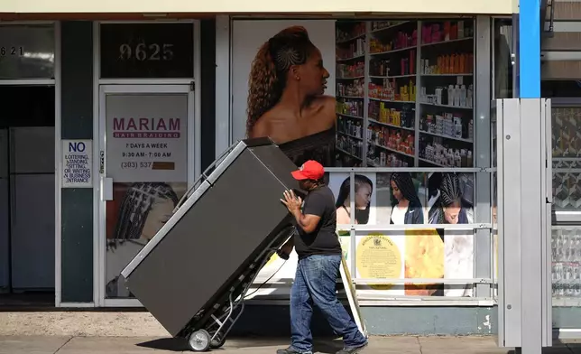 A worker wheels a refrigerator into a used appliance store along East Colfax at Dallas Street, Wednesday, Oct. 9, 2024, in the east Denver suburb of Aurora, Colo. (AP Photo/David Zalubowski)