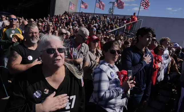 Attendees say the Pledge of Allegiance at a campaign rally for Republican presidential nominee former President Donald Trump at Dodge County Airport, Sunday, Oct. 6, 2024, in Juneau, Wis. (AP Photo/Julia Demaree Nikhinson)