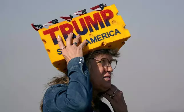 Sandy Kahlow wears a Donald Trump-themed Wisconsin cheese hat before Republican presidential nominee former President Donald Trump arrives to speak at a campaign rally at Dodge County Airport, Sunday, Oct. 6, 2024, in Juneau, Wis. (AP Photo/Julia Demaree Nikhinson)