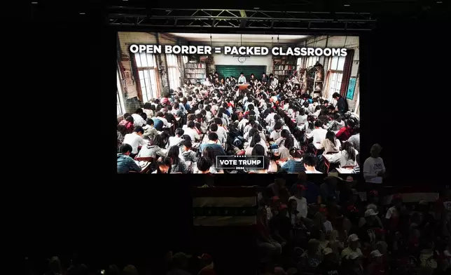 A message about borders and classrooms appears on a video screen as supporters arrive before Republican presidential nominee former President Donald Trump speaks at a campaign rally at Grand Sierra Resort and Casino, Friday, Oct. 11, 2024, in Reno, Nev. (AP Photo/Jae C. Hong)