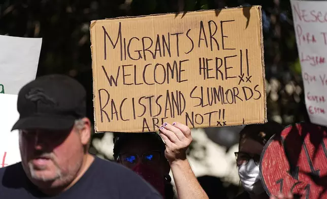 FILE - A person holds up a placard during a rally by the East Colfax Community Collective to address chronic problems in the apartment buildings occupied by people displaced from their home countries in central and South America, Sept. 3, 2024, in Aurora, Colo. (AP Photo/David Zalubowski, File)