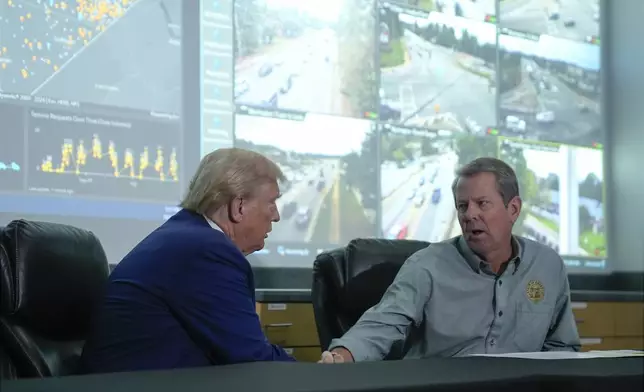 Republican presidential nominee former President Donald Trump talks with Georgia Gov. Brian Kemp during a briefing at the Columbia County Emergency Management Agency as he visits areas impacted by Hurricane Helene, Friday, Oct. 4, 2024, in Evans, Ga. (AP Photo/Evan Vucci)