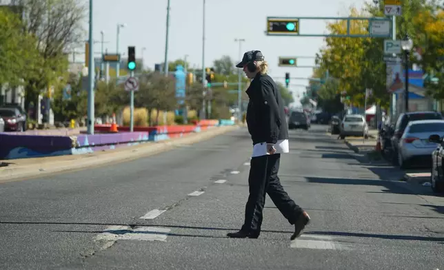 A lone pedestrian crosses East Colfax Avenue at the intersection with Dayton Street, Wednesday, Oct. 9, 2024, in the east Denver suburb of Aurora, Colo. (AP Photo/David Zalubowski)