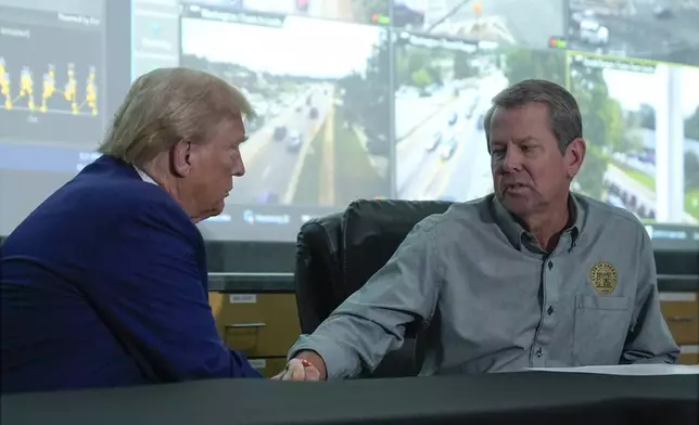 Republican presidential nominee former President Donald Trump talks with Georgia Gov. Brian Kemp during a briefing at the Columbia County Emergency Management Agency as he visits areas impacted by Hurricane Helene, Friday, Oct. 4, 2024, in Evans, Ga. (AP Photo/Evan Vucci)