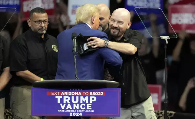 Art del Cueto, vice president of the National Border Patrol Council, embraces Republican presidential nominee former President Donald Trump at a campaign rally at the Findlay Toyota Arena Sunday, Oct. 13, 2024, in Prescott Valley, Ariz. (AP Photo/Ross D. Franklin)