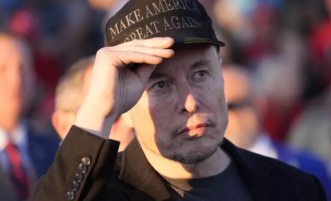 Tesla and SpaceX CEO Elon Musk listens as Republican presidential nominee former President Donald Trump speaks at a campaign event at the Butler Farm Show, Saturday, Oct. 5, 2024, in Butler, Pa. (AP Photo/Alex Brandon)