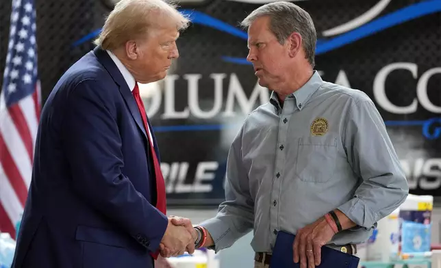 Republican presidential nominee former President Donald Trump shakes hands with Georgia Gov. Brian Kemp after speaking at a temporary relief shelter as he visits areas impacted by Hurricane Helene, Friday, Oct. 4, 2024, in Evans, Ga. (AP Photo/Evan Vucci)