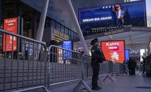 A police officer stands in front of the campaign video boards for Republican presidential nominee former President Donald Trump outside Madison Square Garden, Sunday, Oct. 27, 2024, in New York. (AP Photo/Yuki Iwamura)