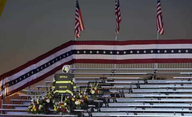 A memorial for firefighter Corey Comperatore, who died as he shielded family members from gunfire, is seen in the bleachers before Republican presidential nominee former President Donald Trump speaks at the Butler Farm Show, the site where a gunman tried to assassinate him in July, Saturday, Oct. 5, 2024, in Butler, Pa. (AP Photo/Alex Brandon)