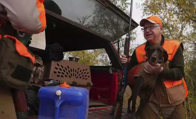 Tim Walz, Minnesota governor and Democratic vice presidential candidate, holds Matt Kucharski's dog Libby, a 6-year-old German Shorthaired Pointer, to give her a drink during the annual Minnesota Governor's Pheasant Hunting Opener near Sleepy Eye, Minn., Saturday, Oct. 12, 2024. (Anthony Souffle/Star Tribune via AP)