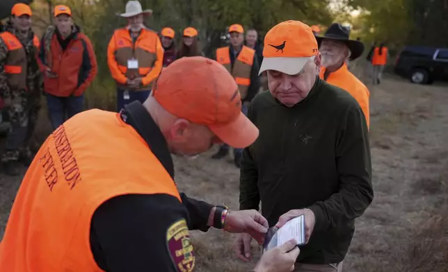 Tim Walz, Minnesota governor and Democratic vice presidential candidate, gets his hunting license ceremoniously inspected before heading out for the annual Minnesota Governor's Pheasant Hunting Opener near Sleepy Eye, Minn., Saturday, Oct. 12, 2024. (Anthony Souffle/Star Tribune via AP)