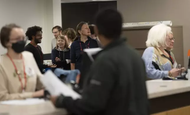 Staff at Ramsey County Elections try to get a look at Minnesota Governor and Vice Presidential candidate Tim Walz as he early votes in St. Paul, Minn., on Wednesday, October 23, 2024. (Renée Jones Schneider/Star Tribune via AP)