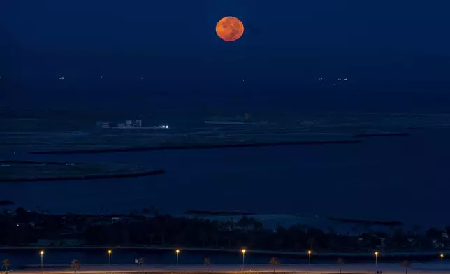 A supermoon sets over the Persian Gulf as dawn breaks in Dubai, United Arab Emirates, Thursday, Oct. 17, 2024. (AP Photo/Altaf Qadri)