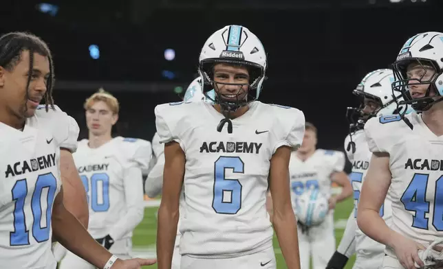 NFL Academy player Rafael Varona Blackstad, center, listens to the coach after a football game between the NFL Academy team and De La Salle High School, Tuesday, Oct. 8, 2024, in London. (AP Photo/Kin Cheung)