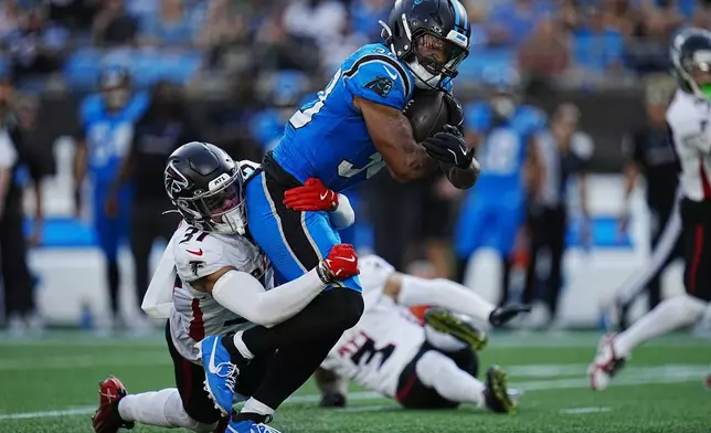 Carolina Panthers running back Chuba Hubbard (30) runs the ball against Atlanta Falcons safety Justin Simmons (31) in the first half of an NFL football game in Charlotte, N.C., Sunday, Oct. 13, 2024. (AP Photo/Rusty Jones)