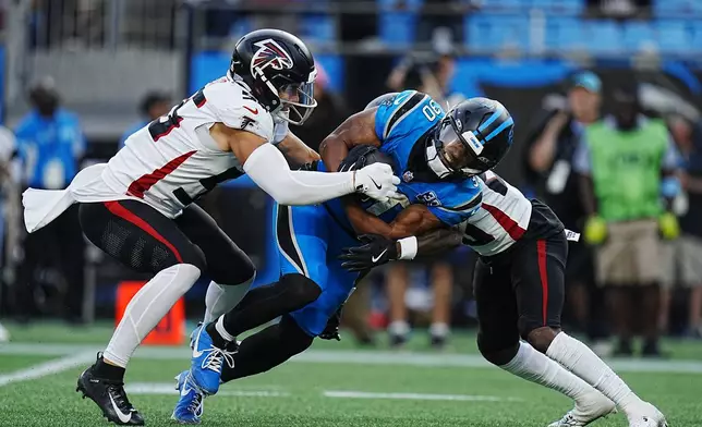 Carolina Panthers running back Chuba Hubbard (30) runs the ball and is tackled by Atlanta Falcons linebacker Kaden Elliss (55) in the first half of an NFL football game in Charlotte, N.C., Sunday, Oct. 13, 2024. (AP Photo/Rusty Jones)