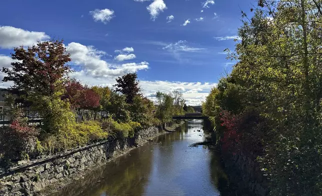 The leaves start to change by the canal under the Chestnut Street bridge in Lewiston, Maine, on Thursday, Oct. 15, 2024. (AP Photo/ Patrick Whittle)