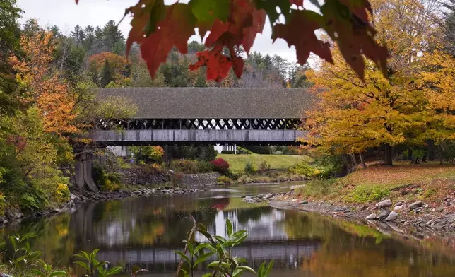 Trees changing to Autumn colors surround the Middle Covered Bridge, which spans the Ottauquechee River, Tuesday, Oct. 15, 2024, in Woodstock, Vt. (AP Photo/Charles Krupa)