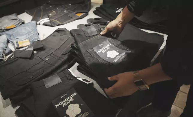 Shop clerk Yuta Akagi displays the jeans at Momotaro Jeans shop in Tokyo, on Sept. 18, 2024. (AP Photo/Eugene Hoshiko)