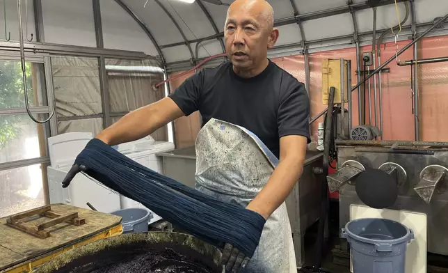 Dyeing craftsman Yoshiharu Okamoto shows how he dyes the threads in indigo for denim at Momotaro Jeans in Kojima, Okayama prefecture, Japan, on Sept. 4, 2024. (AP Photo/Yuri Kageyama)