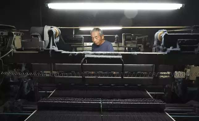 Shigeru Uchida, a weaver at Momotaro Jean, examines a vintage loom machine in Kojima, Okayama prefecture, western Japan, on Sept. 4, 2024. (AP Photo/Ayaka McGill)